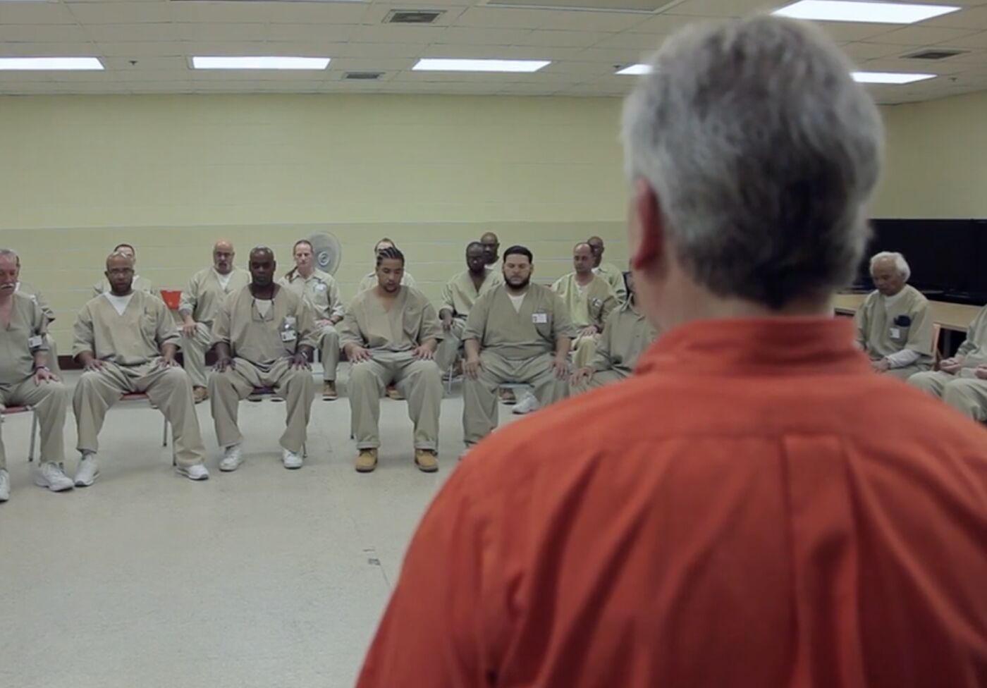 A large seated circle of participants in a prison mindfulness program